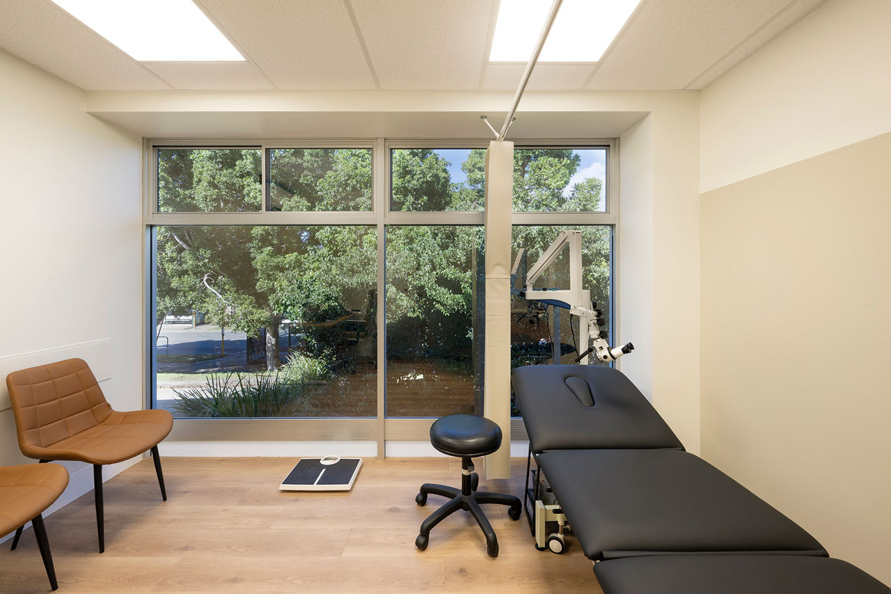 White and tan treatment room interior fitout for Keperra Medical Centre with examination table